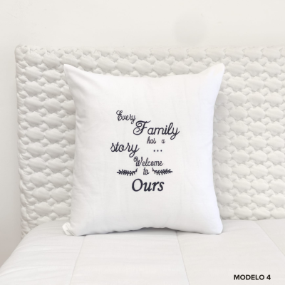 Almofada branca com texto decorativo preto sobre cama com cabeceira acolchoada branca.