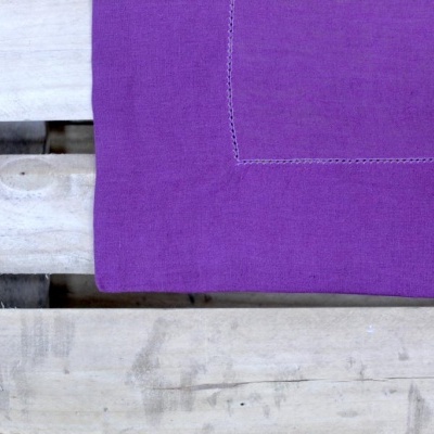 Canto de tecido lilás com costura decorativa sobre superfície de madeira clara