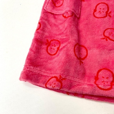 Detalhe de roupa cor de rosa com padrão de maçãs vermelhas e textura felpuda