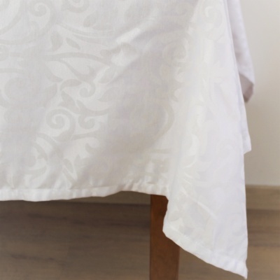 Toalha de mesa branca com padrão floral texturado sobre mesa de madeira