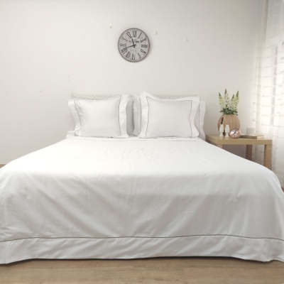 Cama de casal com roupa de cama branca e relógio de parede vintage