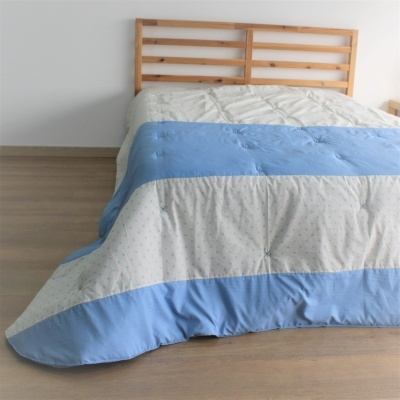 Cobertor listrado azul e creme em cama de madeira em quarto minimalista