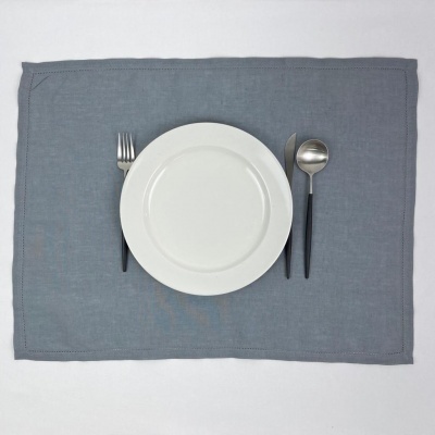 Conjunto de jantar com prato branco e talheres de cabo preto sobre placemat cinzento
