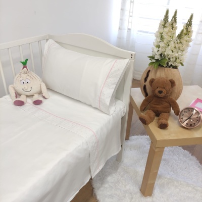 Cama de bebé com lençóis brancos e peluches em quarto claro e decorado