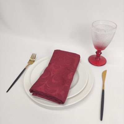 Conjunto de pratos com guardanapo vermelho, talheres com cabo preto e copo de vidro texturizado vermelho