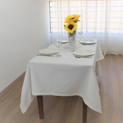 Mesa posta com toalha branca, pratos, copos e vaso com girassóis