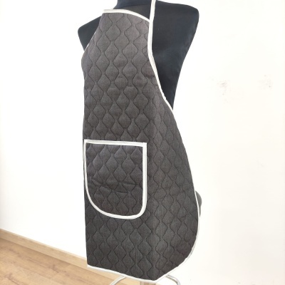 Avental cinza escuro acolchoado com bolso e bordas brancas num manequim preto