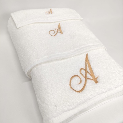 Conjunto de toalhas brancas com bordado dourado da letra A.