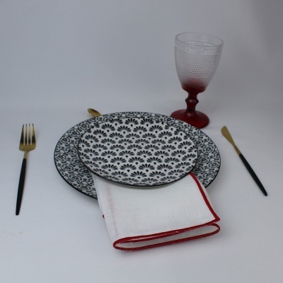 Conjunto de jantar com pratos decorados, talheres e copo em fundo branco