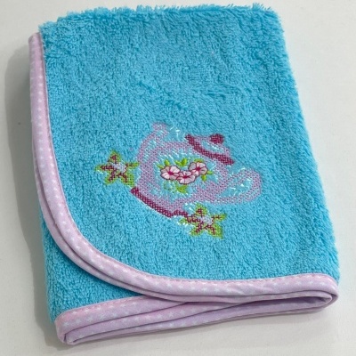 Toalha azul com bordado de bule e flores, bordadura lilás com pontos brancos