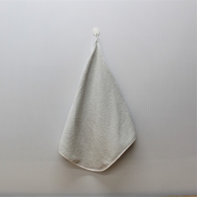 Toalha de banho branca pendurada numa parede cinzenta