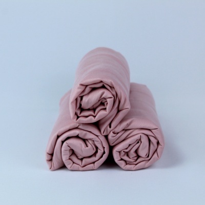 Três mantas ou lençóis rosa claro enrolados em fundo branco