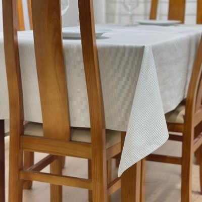 Mesa de madeira clara com toalha branca e cadeiras de madeira clara com bancos estofados em tecido bege