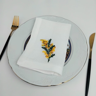 Conjunto de talheres, prato branco e guardanapo bordado com flores amarelas