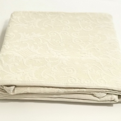 Colcha bege claro com padrão em arabescos dobrada