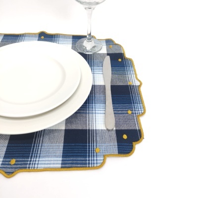 Lugar americano xadrez azul com pratos brancos, faca e copo