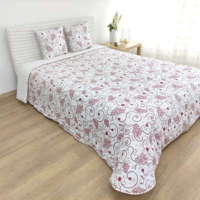 Colcha e almofadas com padrão floral em cama branca em quarto minimalista