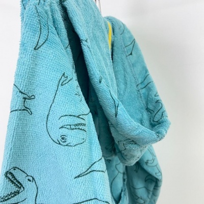 Toalha azul-turquesa com desenhos de dinossauros a preto pendurada.