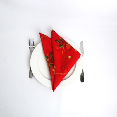 Conjunto de prato branco com talheres ao lado e guardanapo vermelho decorado em tecido