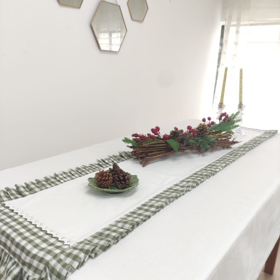 Caminho de mesa branco bordado sobre tecido xadrez verde e branco com decorações festivas