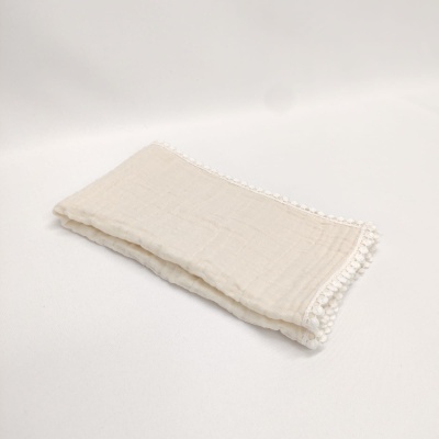 Pano bege claro com pompons brancos na borda