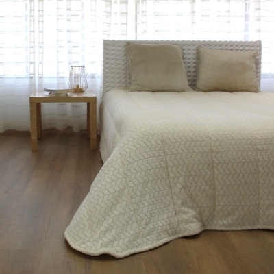 Cama com colcha e almofadas bege claro e mesa de cabeceira de madeira