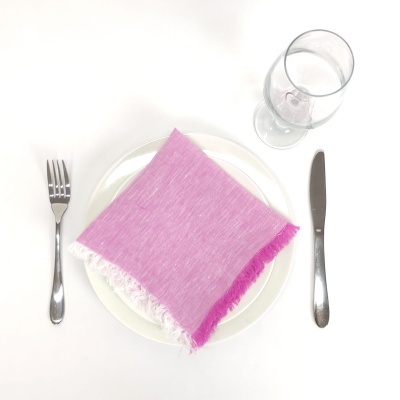 Mesa posta com prato branco, guardanapo rosa e talheres de metal