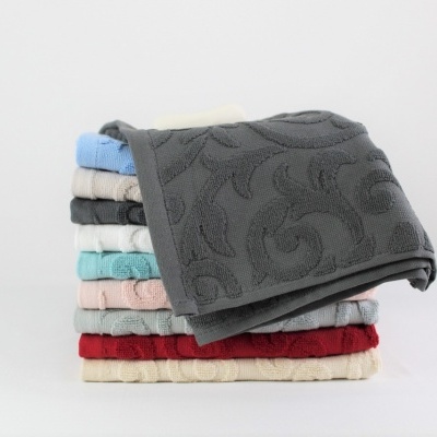 Pilhas de toalhas de banho coloridas dobradas com padrão floral em ambiente neutro