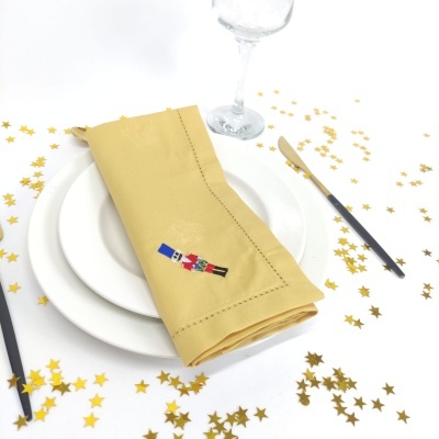 Guardanapo amarelo bordado com soldado do exército em prato branco com talheres e confetes dourados