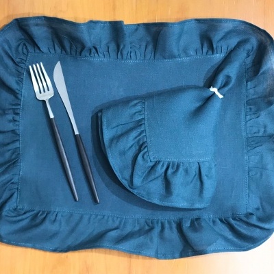 Repousa-talheres azul com talheres e porta-talheres em tecido sobre madeira