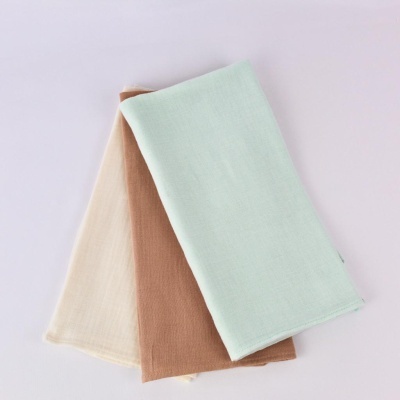 Três panos de prato em algodão ou linho em cores pastel sobre fundo branco.