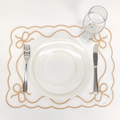 Conjunto de prato, talheres e copo sobre base branca bordada dourado