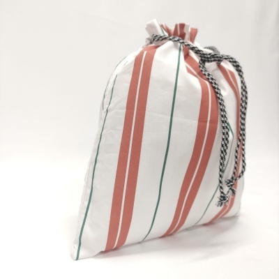 Saco de tecido branco com riscas vermelhas e verdes e cordão preto e branco