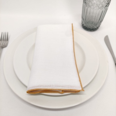 Conjunto de pratos brancos com guardanapo branco e talheres numa mesa de jantar