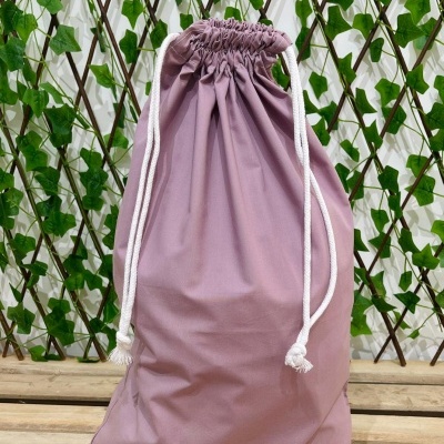 Saco de tecido cor de rosa com cordão branco e fundo verde