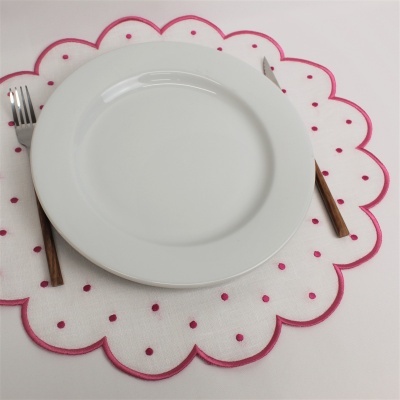 Prato branco sobre individual branco com pontos e bordas cor-de-rosa, garfo e faca ao lado