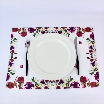 individual de mesa com padrão floral, prato branco, garfo e faca sobre superfície branca