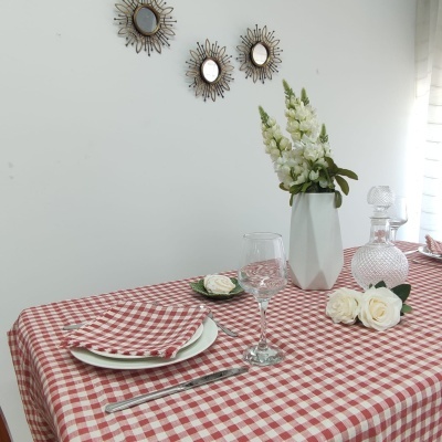 Toalha de mesa xadrez vermelha e branca com arranjo floral branco e espelhos decorativos na parede
