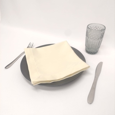 Conjunto de jantar com prato cinzento, guardanapo creme, talheres metal e copo vidro