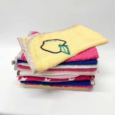 Toalhas coloridas empilhadas com uma toalha amarela bordada com um limão.