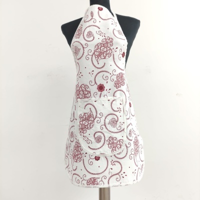 Avental branco com padrão vermelho e bolso frontal em manequim preto