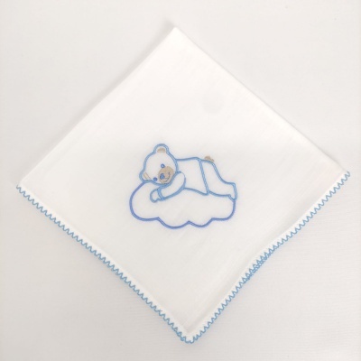 Lenço branco com ursinho azul bordado sobre nuvem azul.