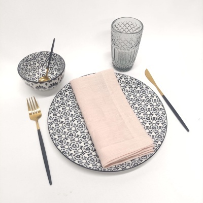 Conjunto de jantar com prato, taça, guardanapo, copo, garfo e colher em superfície branca