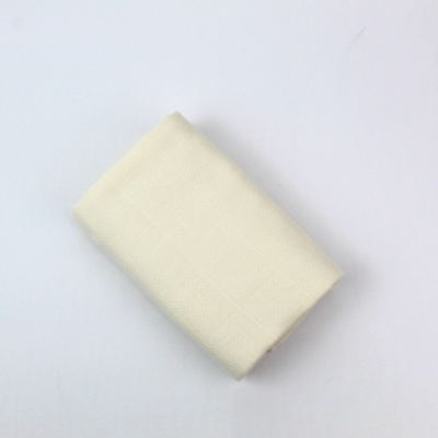 peça de tecido bege claro dobrada sobre superfície branca