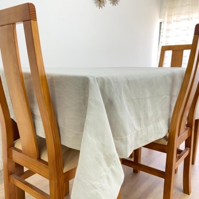 Mesa de jantar em madeira clara com toalha bege e três cadeiras