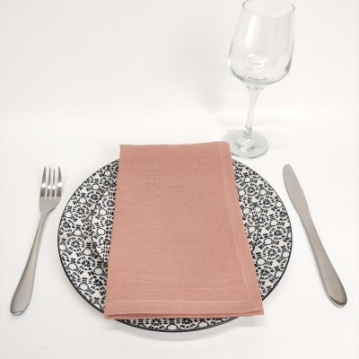 Conjunto de jantar com prato de cerâmica padrão preto e branco, toalha rosa, talheres metálicos e copo de vidro