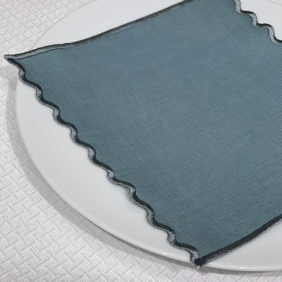 Guardanapo azul escuro com bordas onduladas sobre tampa branca