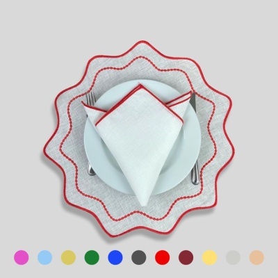 Conjunto de jantar com guardanapo branco e prato branco sobre toalha branca com borda vermelha ondulada