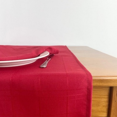 toalha de mesa vermelha com prato branco e garfo sobre mesa de madeira clara