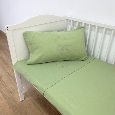 cama de criança branca com roupa de cama verde clara e bordado de balão